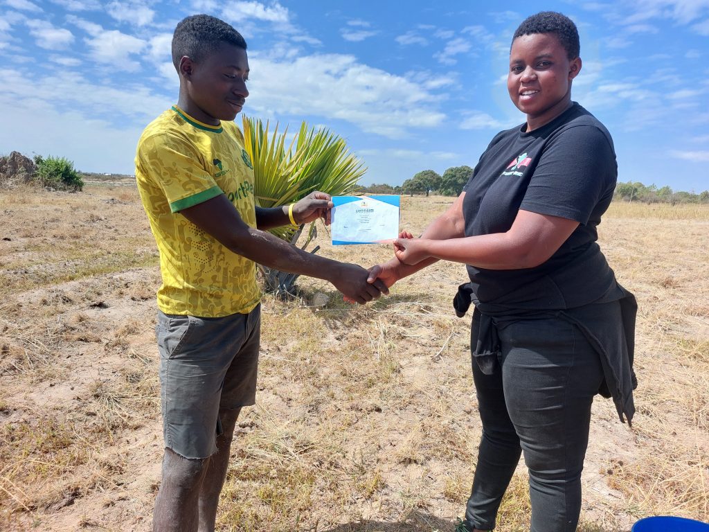 Field officer presents certificate to young farmer