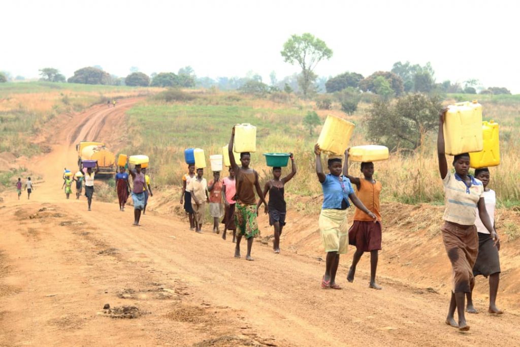 Women and girls in Uganda carrying water from the river