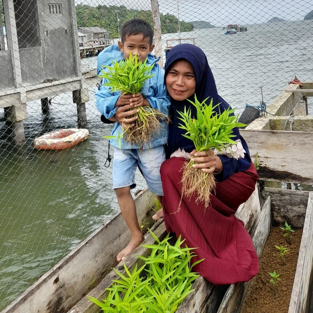 Nurmi and one of her children hold harvested kangkong