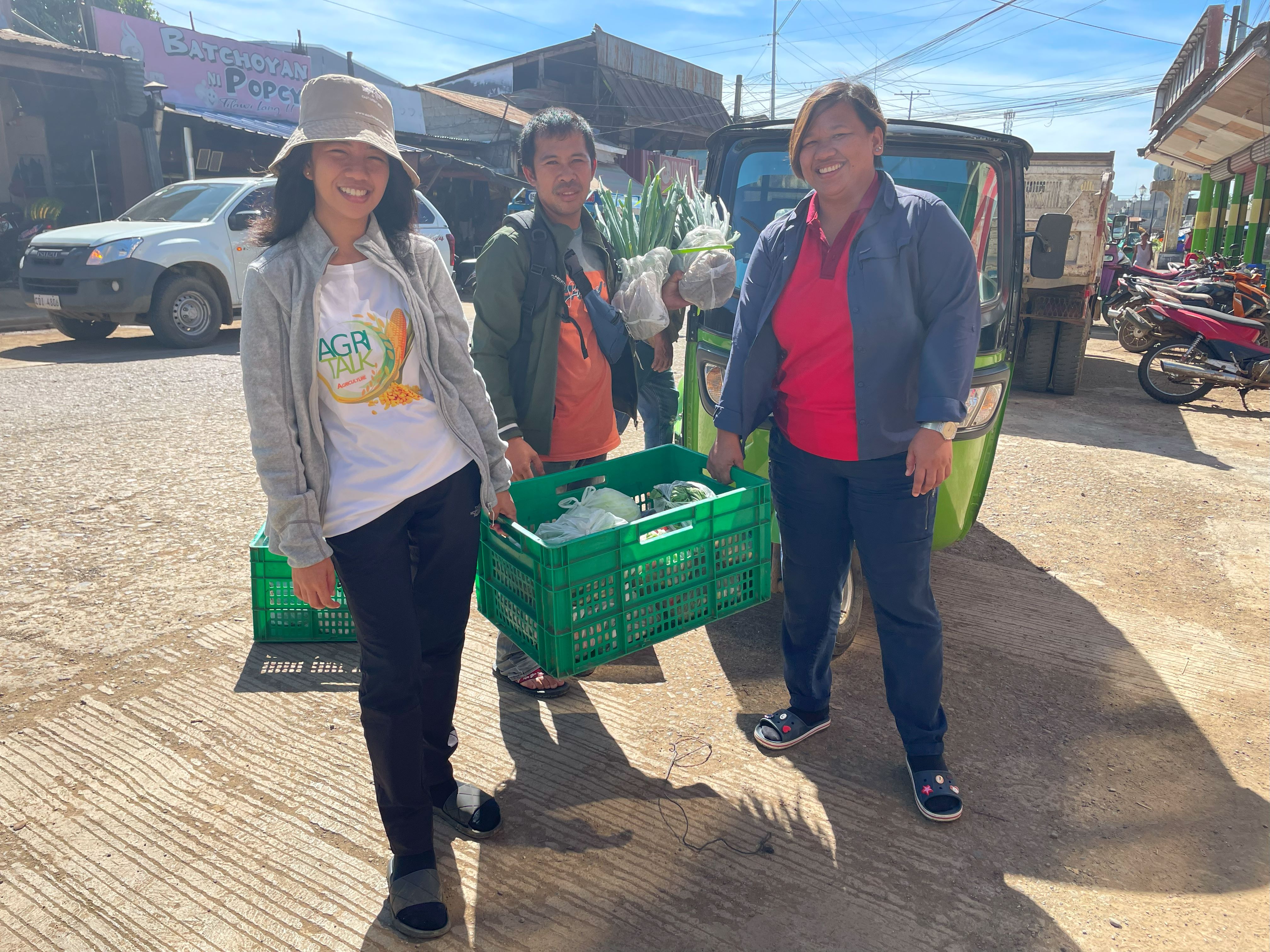 Knowledge Transfer Specialist Aila Irizsa Ibanez and EWS-KT Technical Support Hub Manager Lysette Lacambra help farmer Rolly Cutang deliver vegetables to consolidator Centro Supersales, Inc., in Bukidnon, Philippines