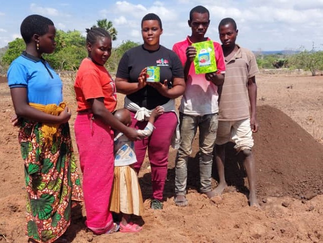Samson Masalu and family stand with TFO Winnie Kessy in a not-yet-planted field.