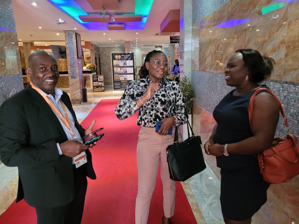 Epaphras Milambwe (Knowledge Transfer Manager for Tanzania), Dianah Orinda (East-West Seed Business Development Manager for Kenya) and Annet Kiiza (East West Seed Business development Manager for Tanzania), talk in a hallway at the summit.