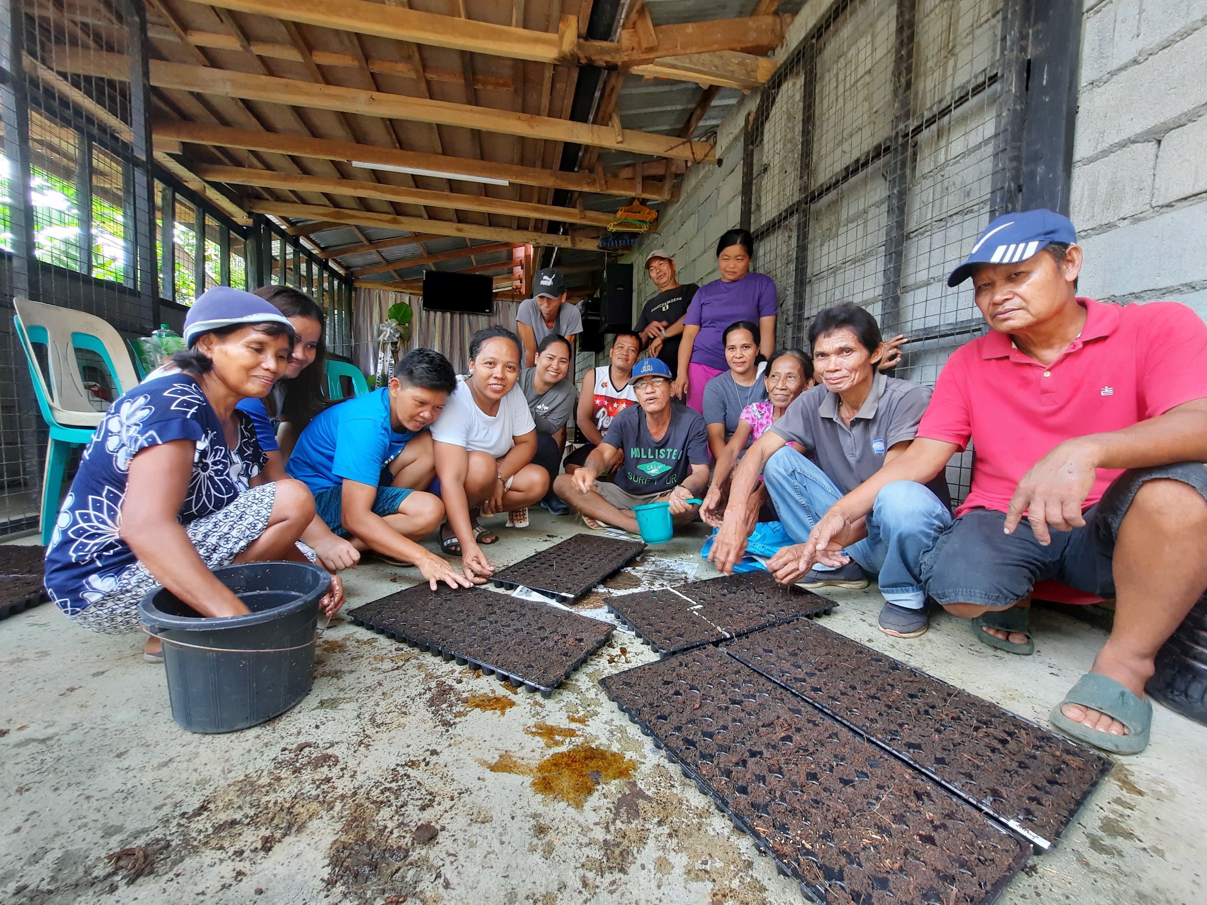 A group of female and male farmers prepare seedling trays