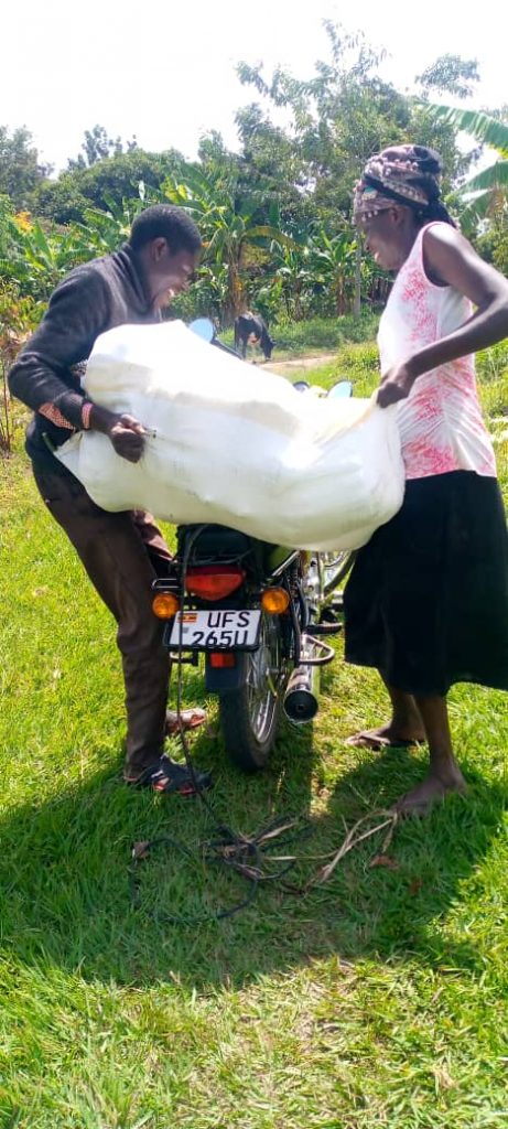 Farmer Cynthia Anyango helps a buyer load a large bag of pumpkins onto his motorcycle.
