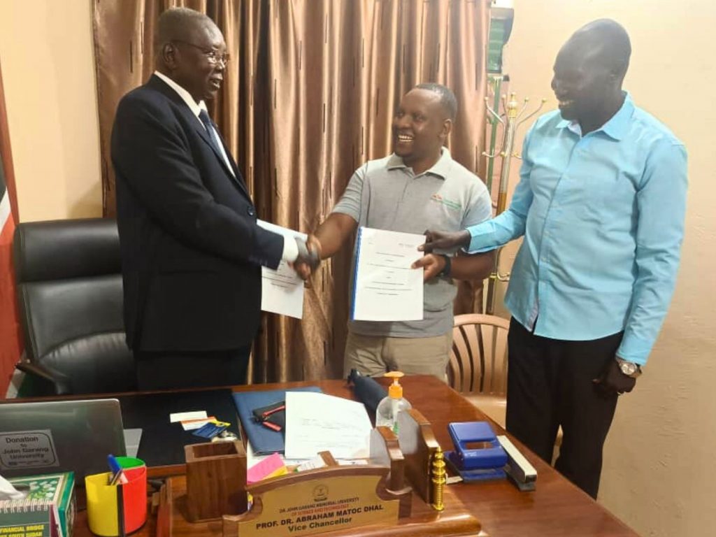 Dr. John Garang University Vice Chancellor, Prof. Dr. Abraham Matoc Dhal, shakes hands with EWS-KT Uganda Knowledge Transfer Manager Joshua Mwanguhya as the acting Dean of the College of Agriculture, Associate Professor Majok Ayuen Kok, looks on.