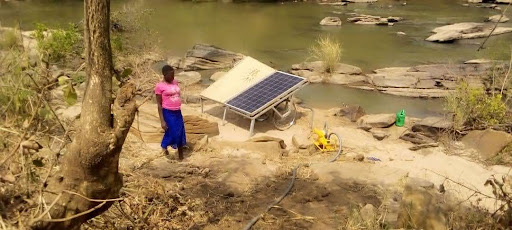 Woman standing near solar irrigation pump next to a river.