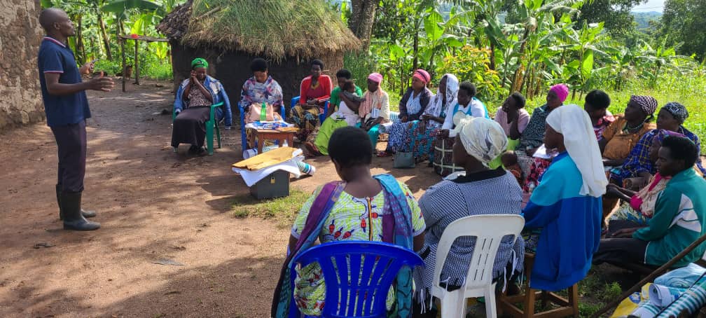 EWS-KT staff member introduces the SMILES project to a group of seated farmers in Kyaka II