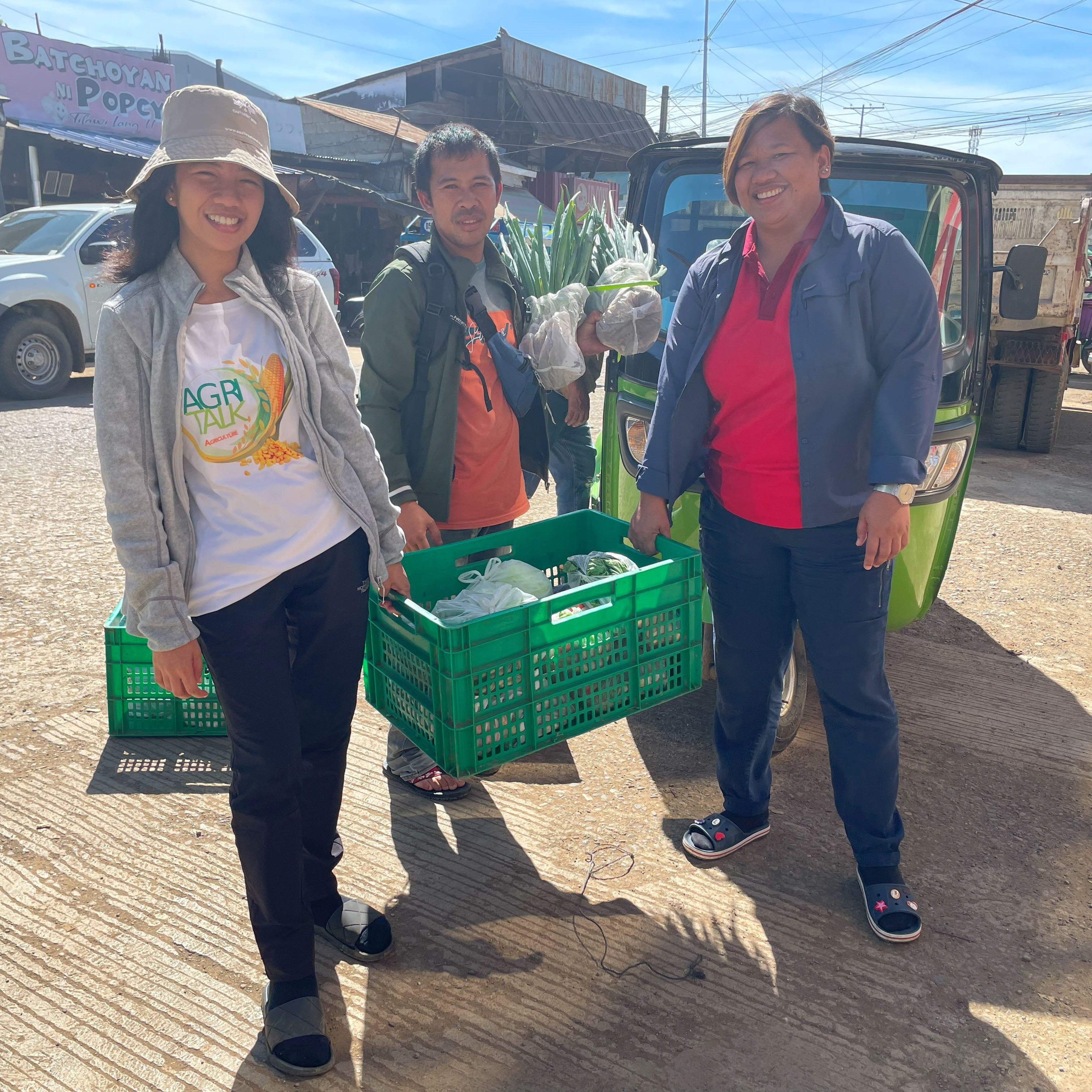 Knowledge Transfer Specialist Aila Irizsa Ibanez and EWS-KT Technical Support Hub Manager Lysette Lacambra help farmer Rolly Cutang deliver vegetables to consolidator Centro Supersales, Inc., in Bukidnon, Philippines.