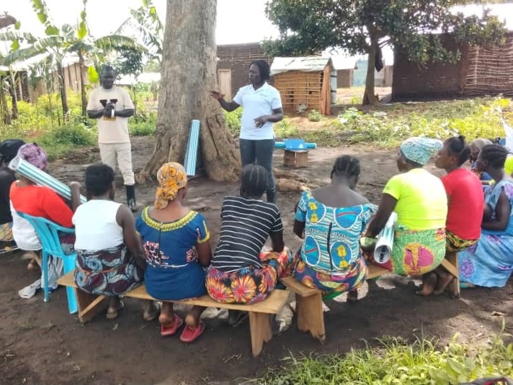 Farmers sit in a semicircle, listening to EWS-KT staff introduce a new project