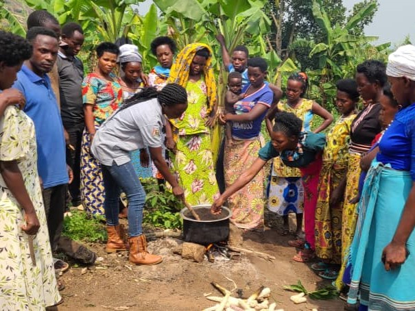 Group of farmers around a pot of soil being heated for sterilization.