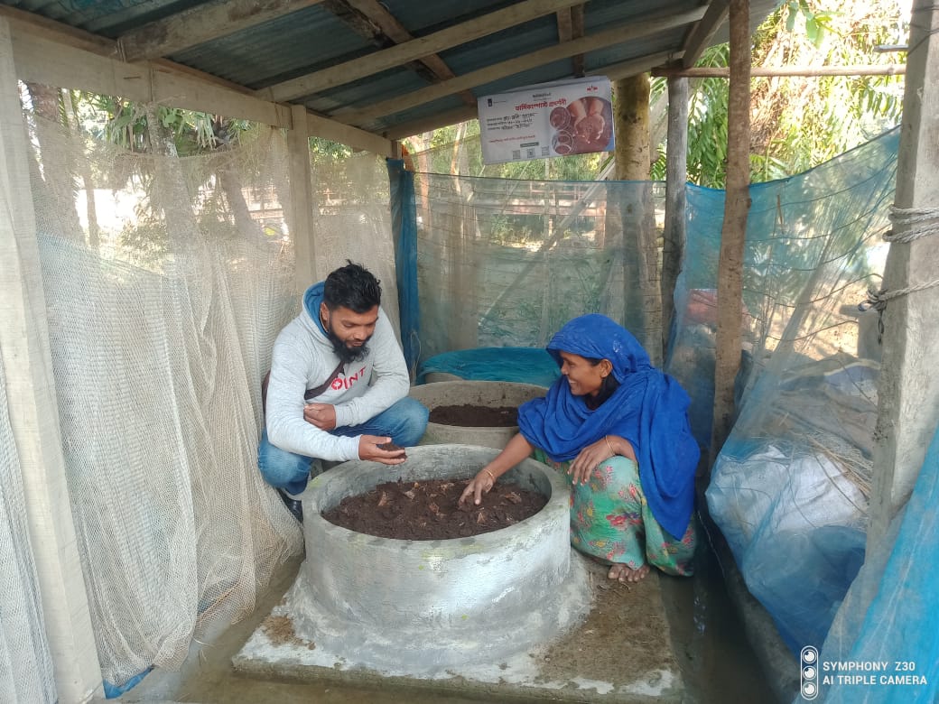EWS-KT male staff member and female farmer inspect her vermicompost operation.
