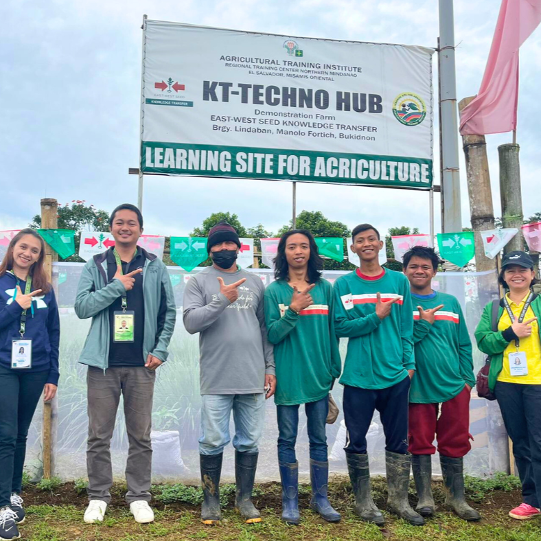 EWS-KT Philippines staff members celebrate PhilGAP certification in front of the KT-Techno Hub learning site sign