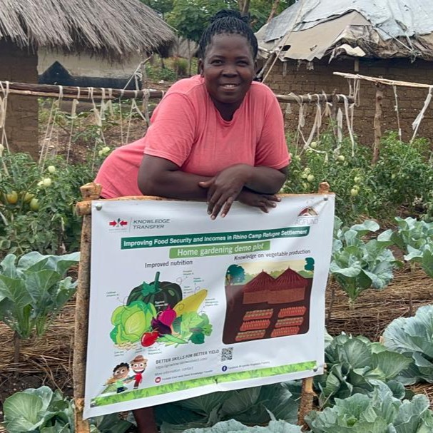 Woman farmer poses with the AGFUND project sign for her home garden.