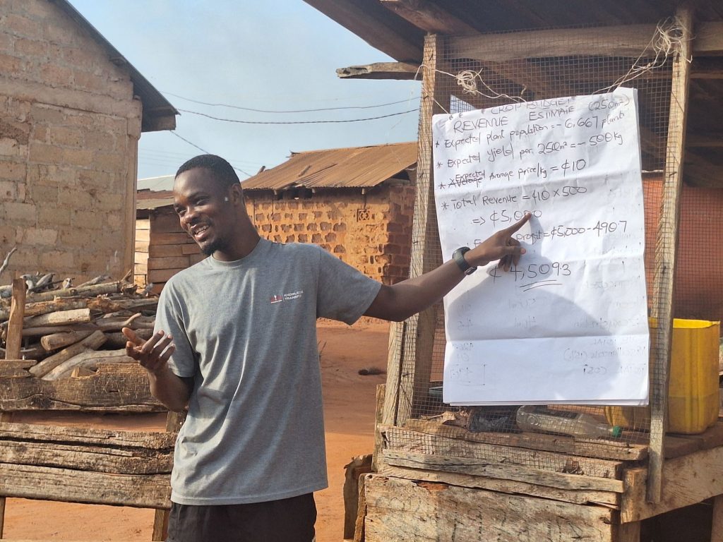 EWS-KT staff member points to revenue estimates on a large piece of paper as he explains return on investment (ROI) to a group of farmers.
