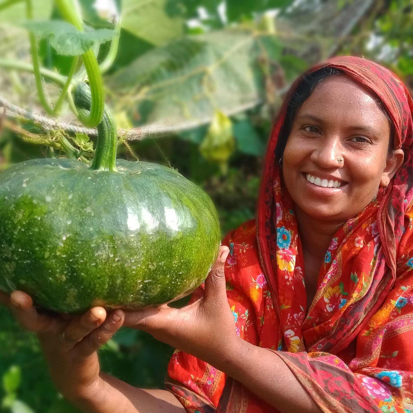 Farmer Asma Akter smiles as she shows off one of her growing pumpkins.