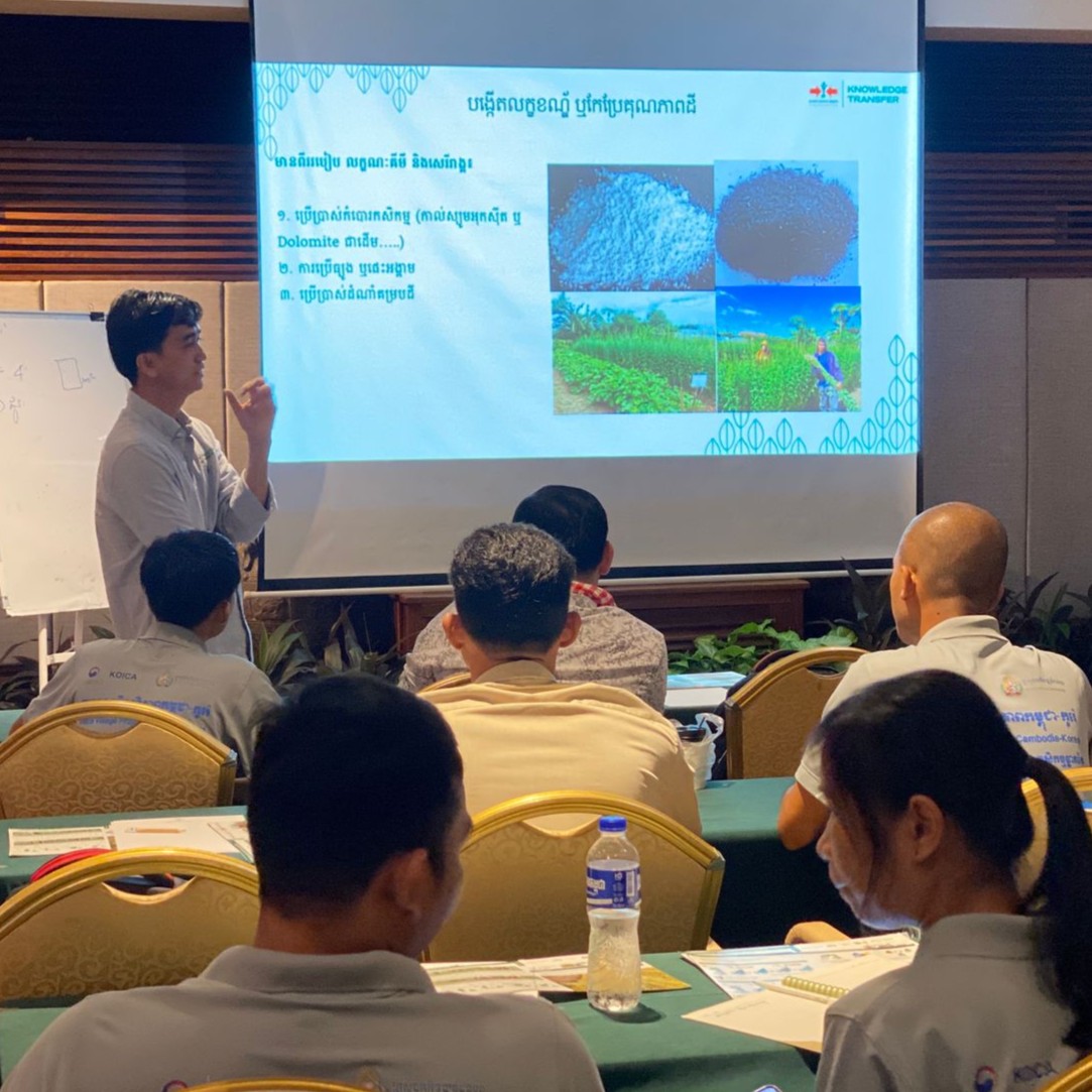 East-West Seed Knowledge Transfer Foundation trainer gestures as he explains a slide during a presentation to other trainers on crop techniques.