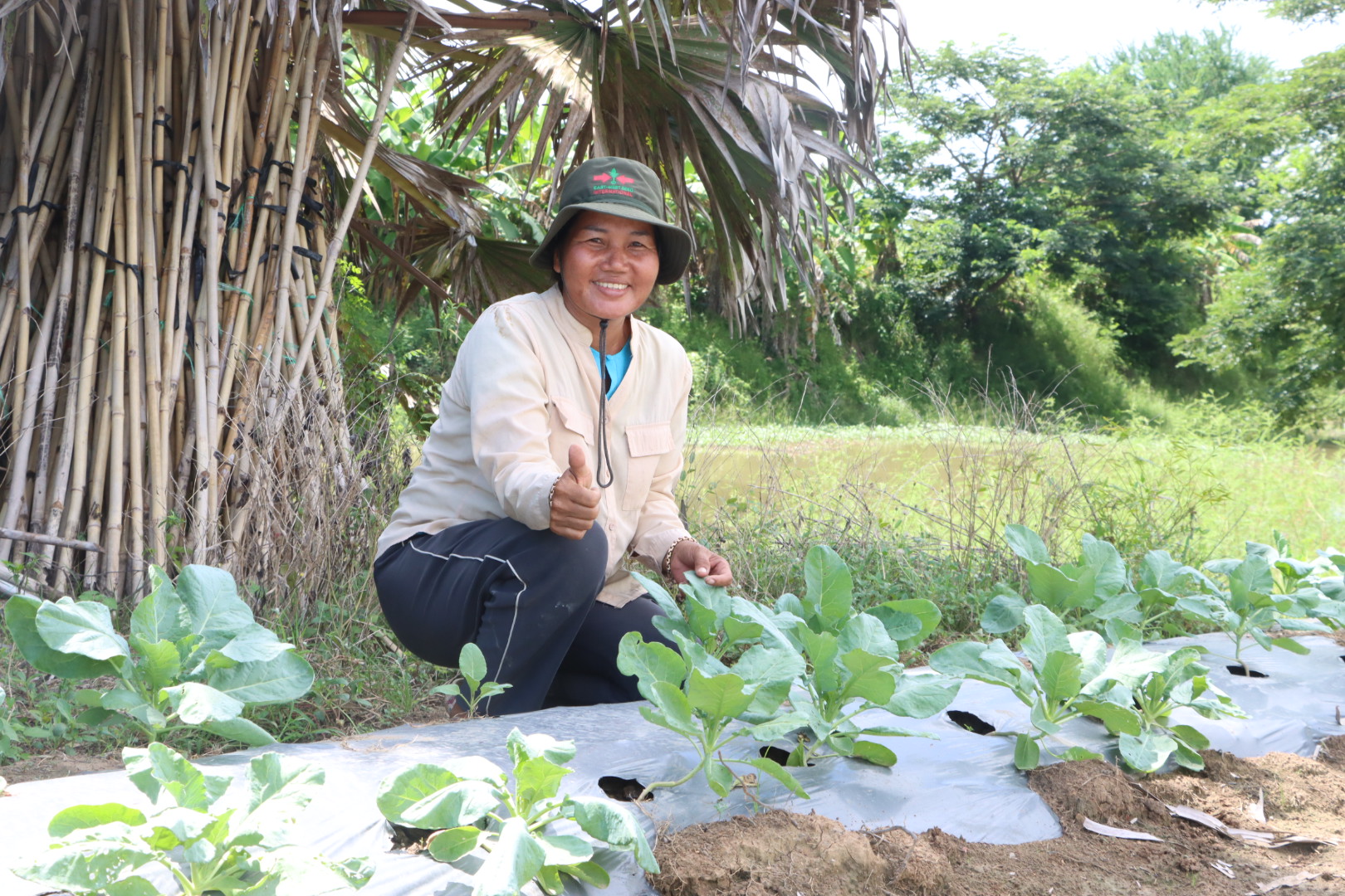 Woman farmer smiles behind a row of healthy plants.