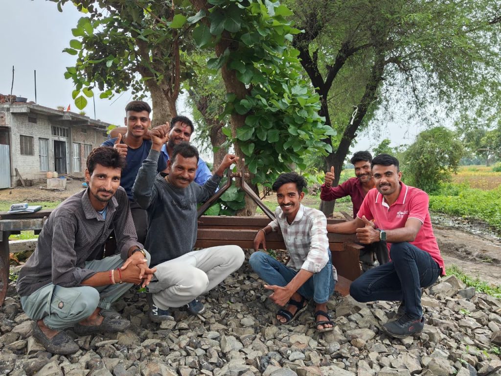 Six men, including farmer Hokam Singh, in front of the farm machine attachment for making raised beds.