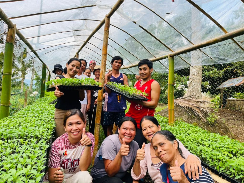 Group of female and male farmers show off their seedlings inside a seedling nursery.