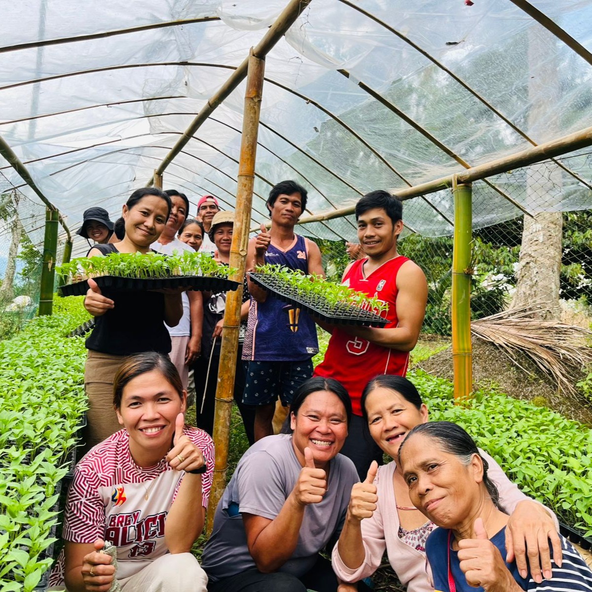 Group of female and male farmers show off their seedlings inside a seedling nursery.