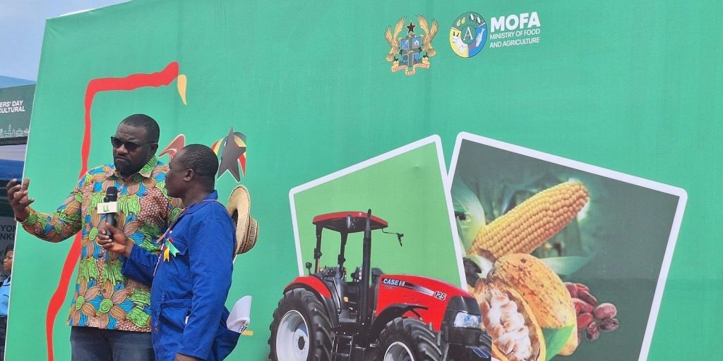 John Setor Dumelo, Ghana's Deputy Minister for Food & Agriculture, is interviewed in front of a National Farmers' Day backdrop.