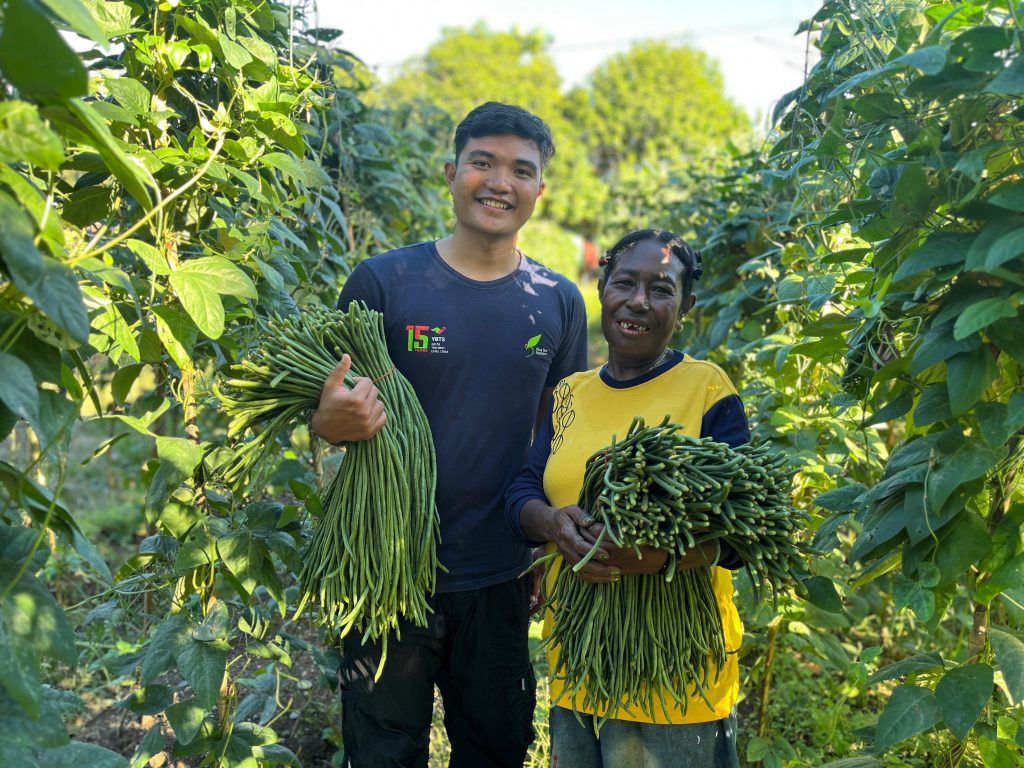 Indonesia farmer Elisabet Fakdewer and YBTS Market Access and Linkage Officer Muhammad Ridlo hold armfuls of yard long beans.