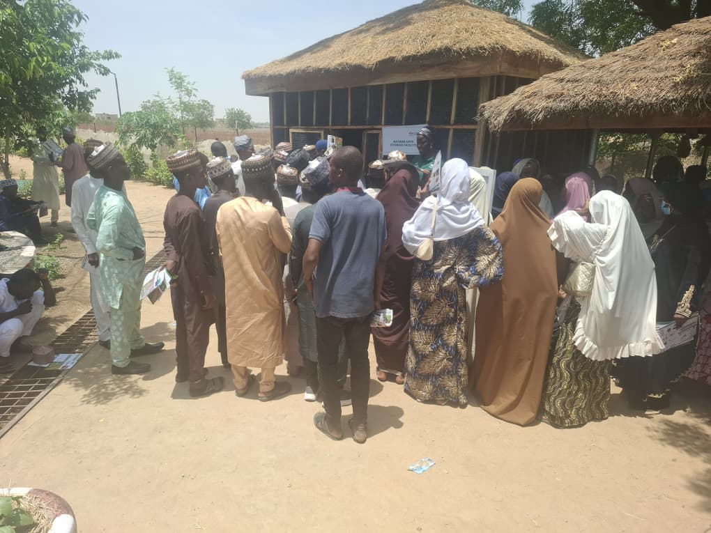 Government agricultural extension agents stand near two types of zero-energy cooling chambers as they learn about post-harvest storage for vegetables.