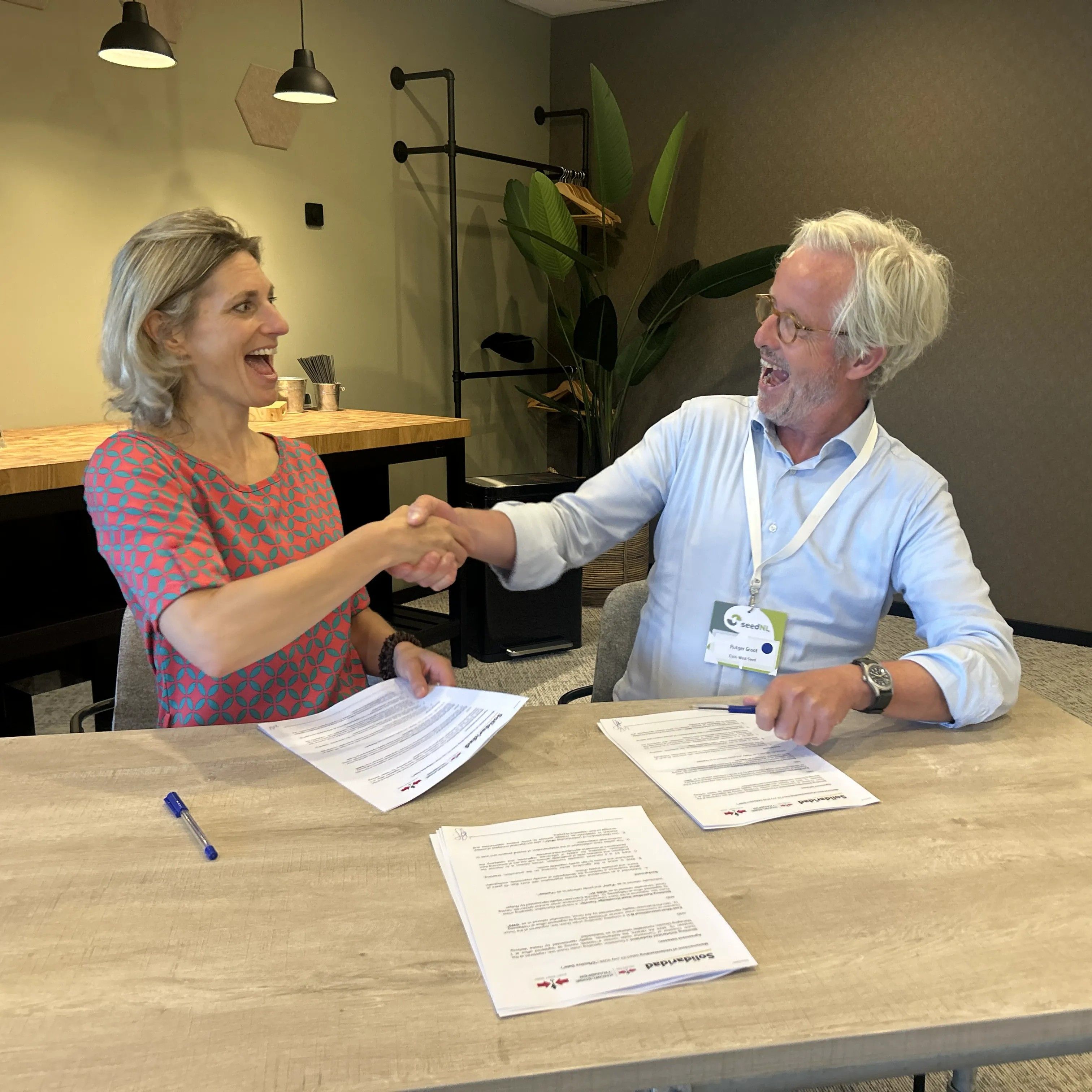 Heske Verburg, Managing Director of Solidaridad Europe, and Rutger Groot, Board Chair of East-West Seed Knowledge Transfer Foundation, shake hands after signing a collaboration agreement between the two organizations.