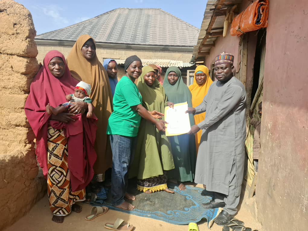 Members of the Jibis Women Group, located in Ikara Local Government Area, Kaduna State, Nigeria, with EWS-KT staff members holding their new government registration document.